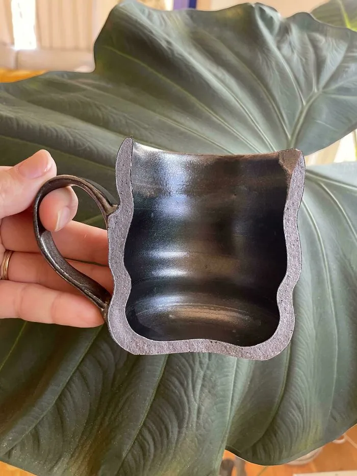 A cross section view of a dark ceramic mug highlighting detailed pottery creations