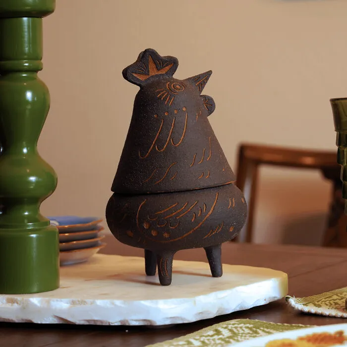 A dark clay chicken shaped container showcasing artistic pottery creations