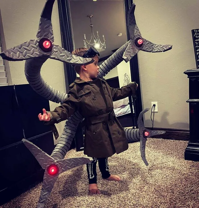 A young boy wearing an elaborate, homemade Doctor Octopus Halloween costume with mechanical tentacles.