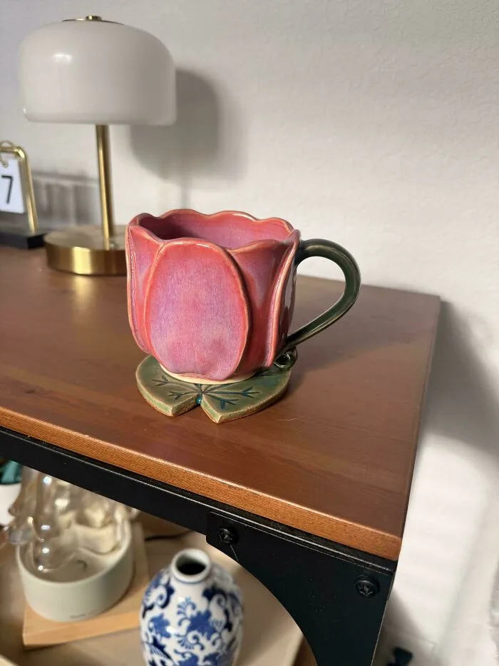 Pink flower-shaped pottery mug sitting on a leaf base