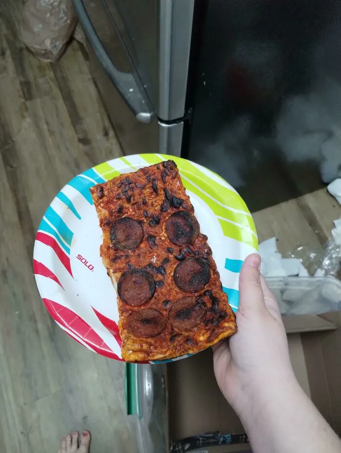 Person holding a paper plate with burnt pepperoni pizza, funny things partners do.