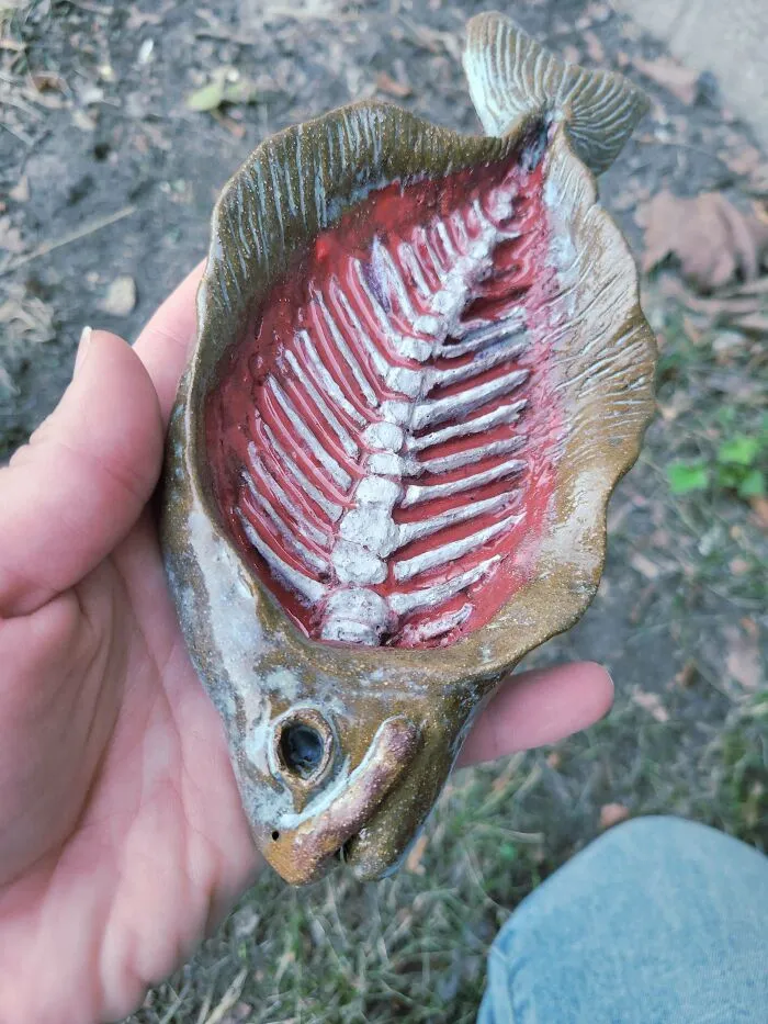 A hand holding a unique fish skeleton trinket dish showcasing creative pottery creations