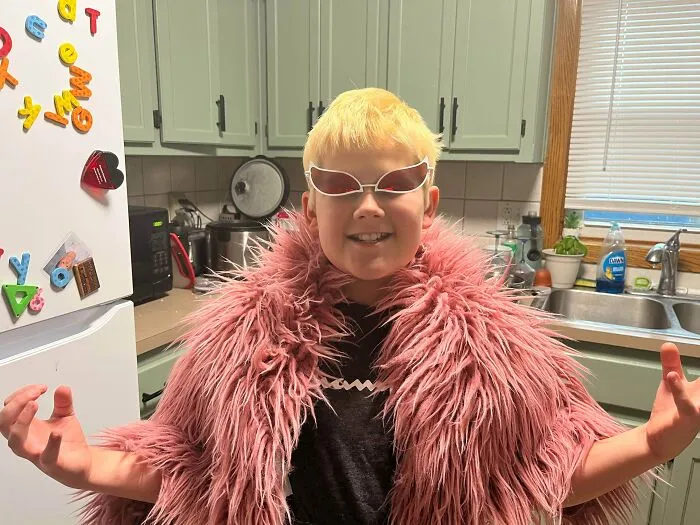 A boy dressed up in a pink fluffy coat and unique sunglasses for creative Halloween costumes.