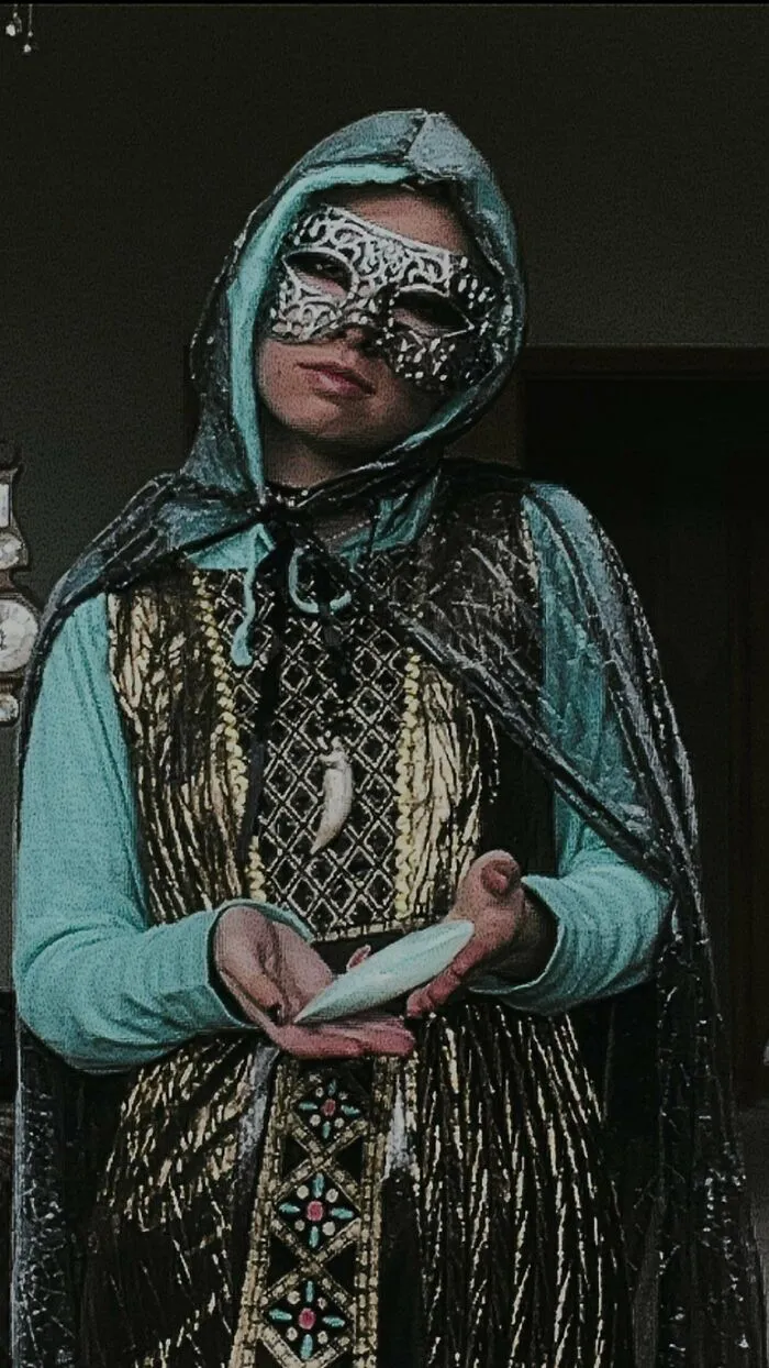A person wearing a elaborate hooded cloak and mask as unique Halloween costumes.