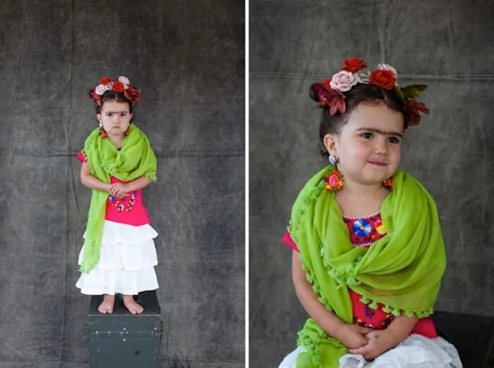 A young girl dressed up in Frida Kahlo kids Halloween costumes with flowers in her hair and a green scarf.