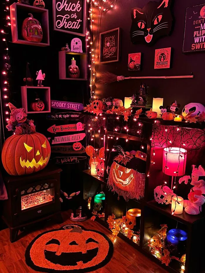 A room filled with spooky Halloween decor, orange lights, glowing jack-o-lanterns, and black cat wall art
