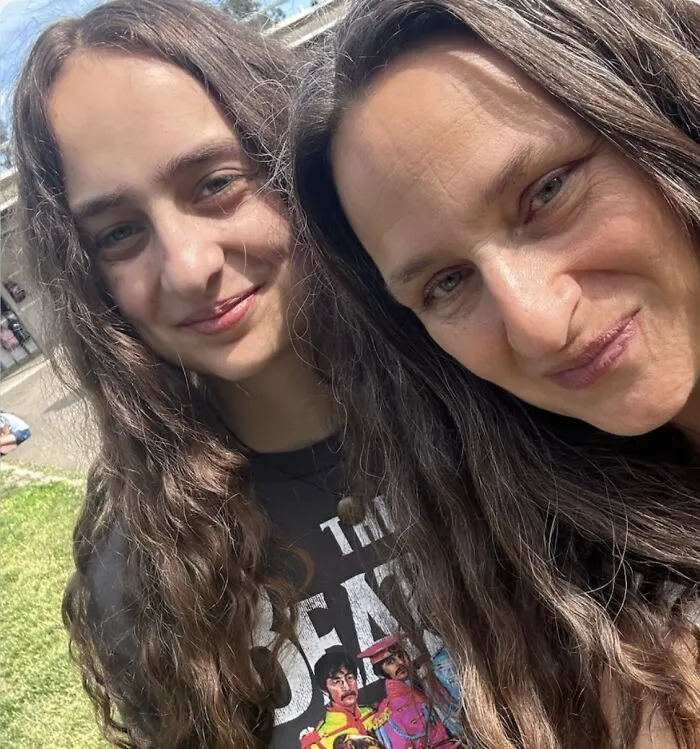Two women smiling with one wearing The Beatles graphic shirt outdoors