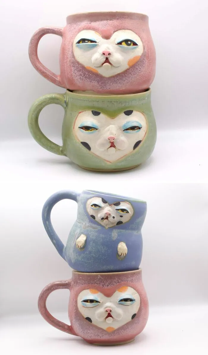 Stacked colorful ceramic mugs featuring whimsical cat faces from unique pottery creations.