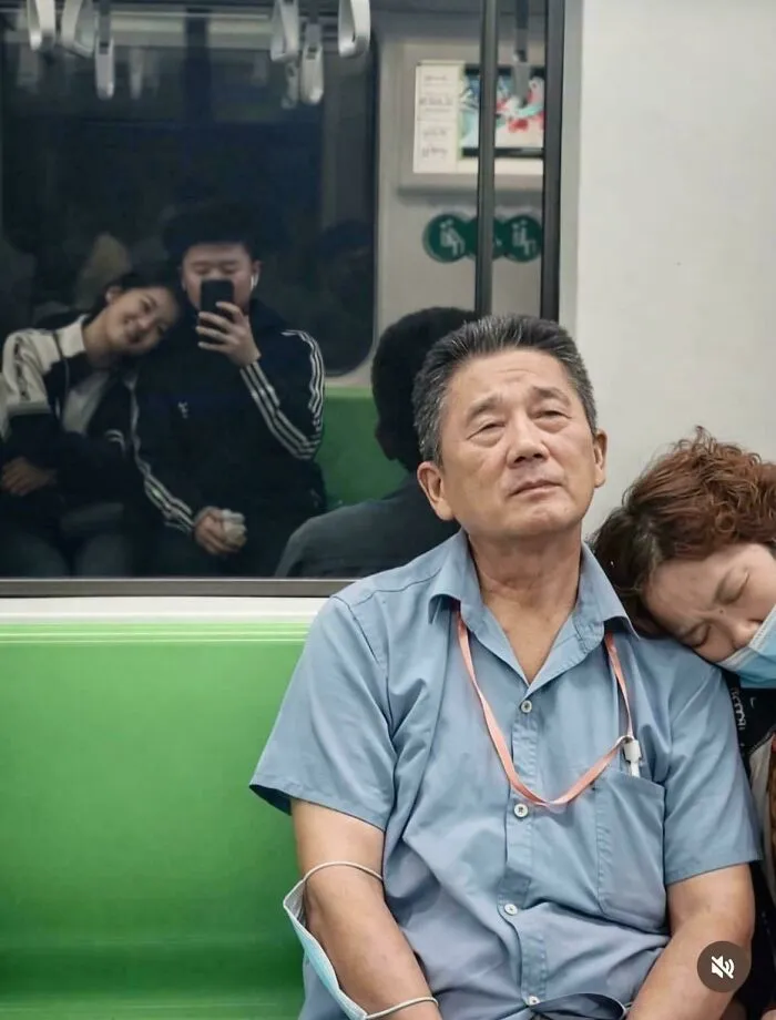 An older couple sitting on a train alongside a reflection of a young couple, showing wholesome moments.