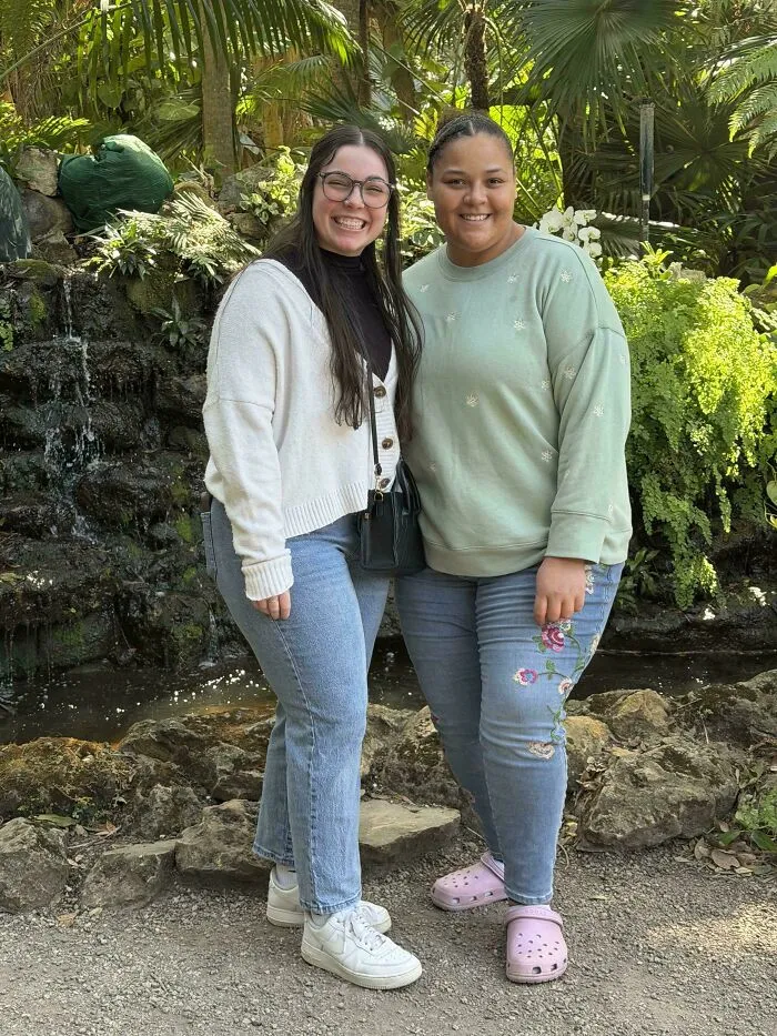 Two smiling friends standing together outdoors, exemplifying wholesome moments of friendship.