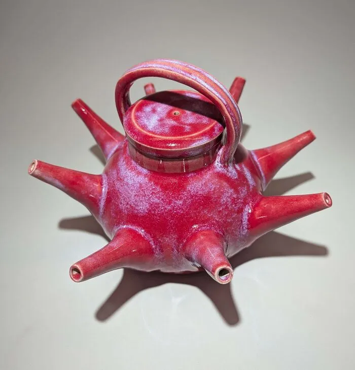 Spiky red teapot displaying unique pottery creations with a multi-spout design