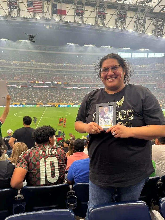 Woman holding a picture framed photo at a stadium, one of the wholesome moments shared on the internet