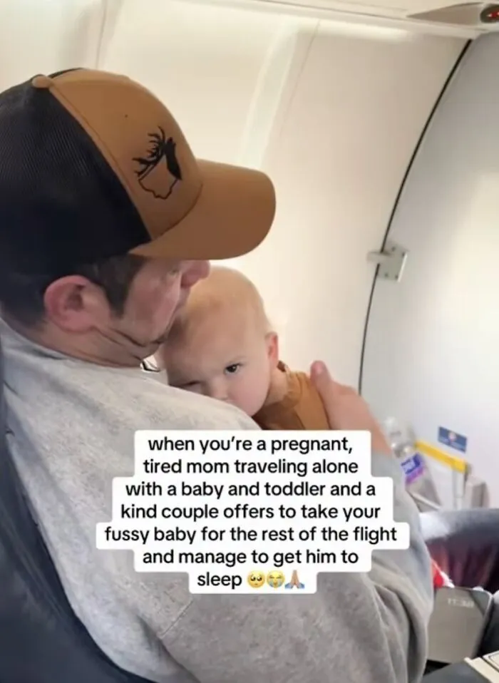 Man holding fussy baby on airplane, capturing wholesome moments.