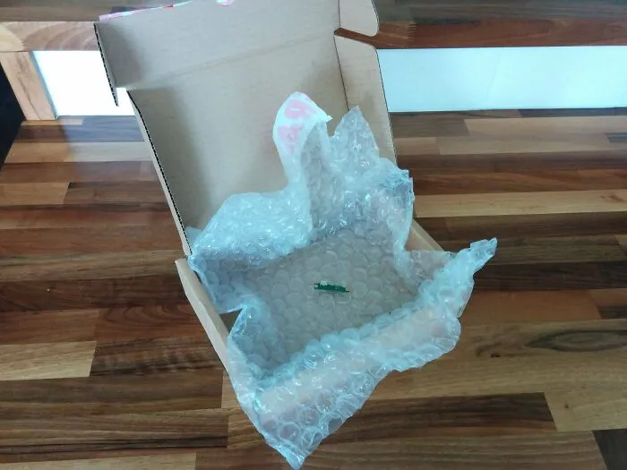 Extremely tiny electronic board inside huge box with bubble wrap showing packaging fails.