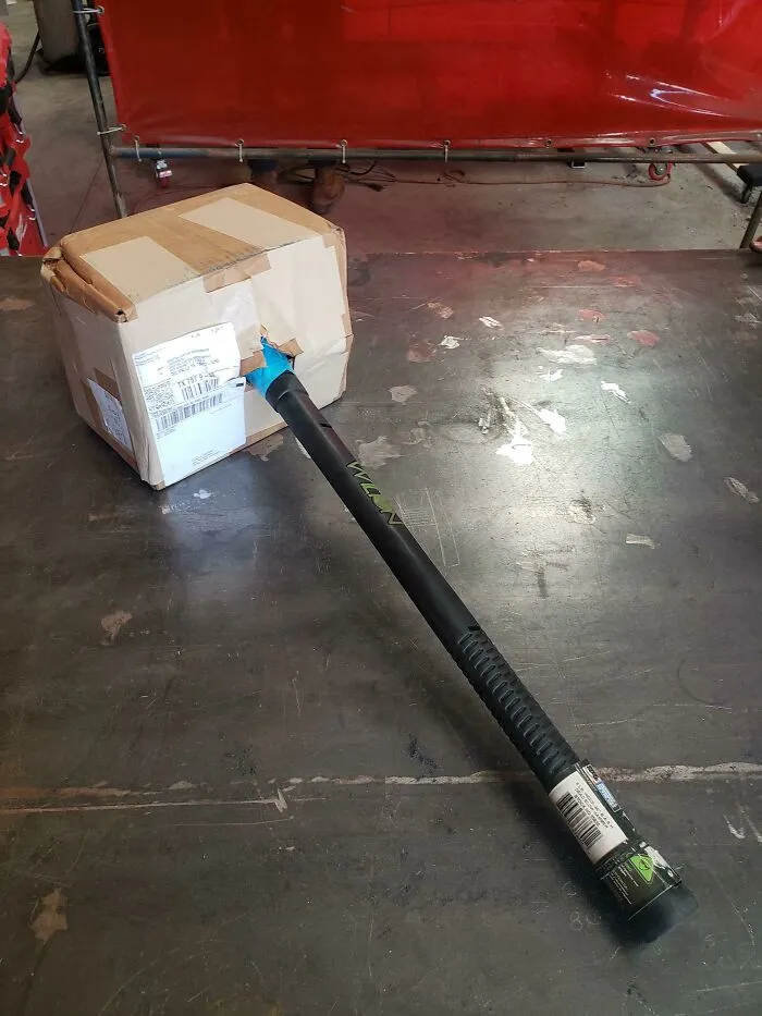 A sledgehammer handle sticking out of a crushed cardboard box, showing bad packaging fails.