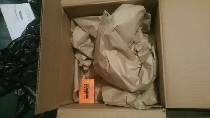 Small orange item in a huge box filled with brown paper as an example of bad packaging fails.
