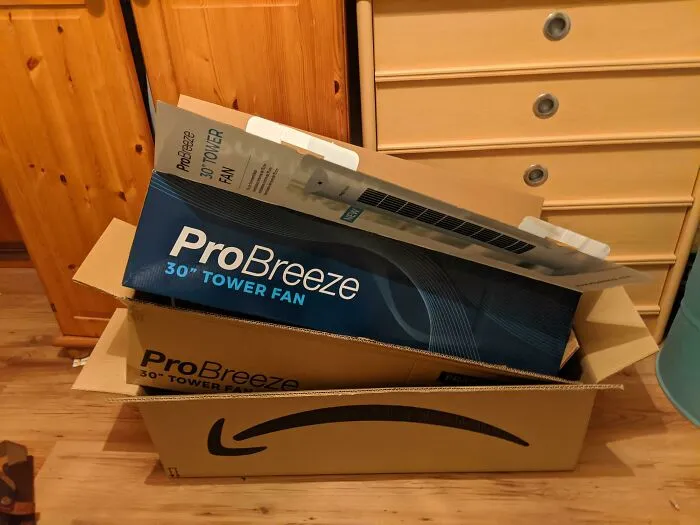 Tower fan product box stuffed awkwardly inside an oversized cardboard shipping box, showing bad packaging fails