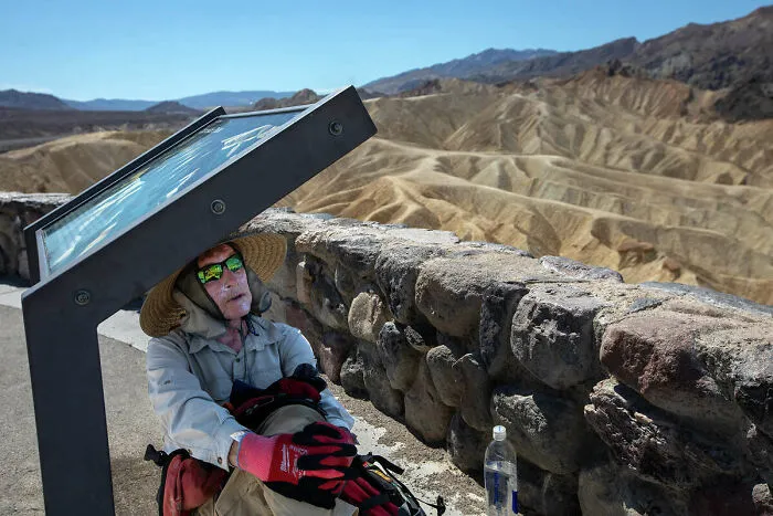 Hiker taking shade under a sign, captured in photos for the last time.