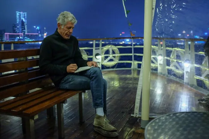 Anthony Bourdain writing in a notepad on a boat, captured in photos for the last time during a trip