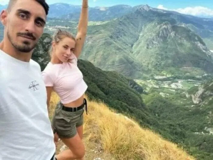 A couple captured in photos for the last time posing on a mountain ridge during a hike.