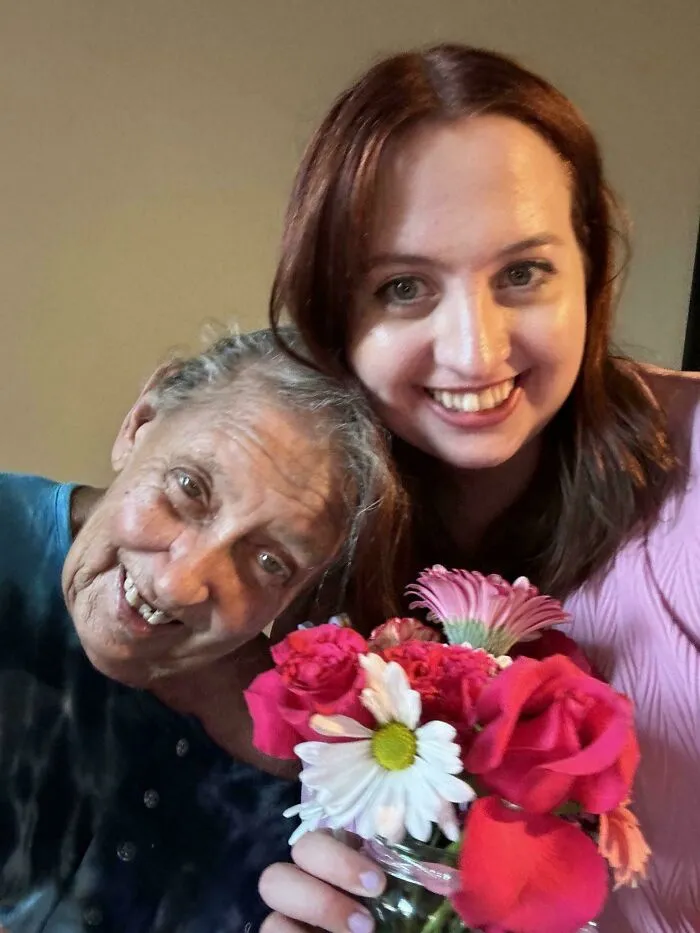 Smiling woman and elderly mother posing with flowers captured in photos for the last time