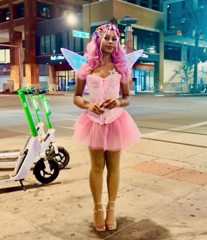 Woman dressed in a bright pink fairy outfit for a creative Halloween costume idea.