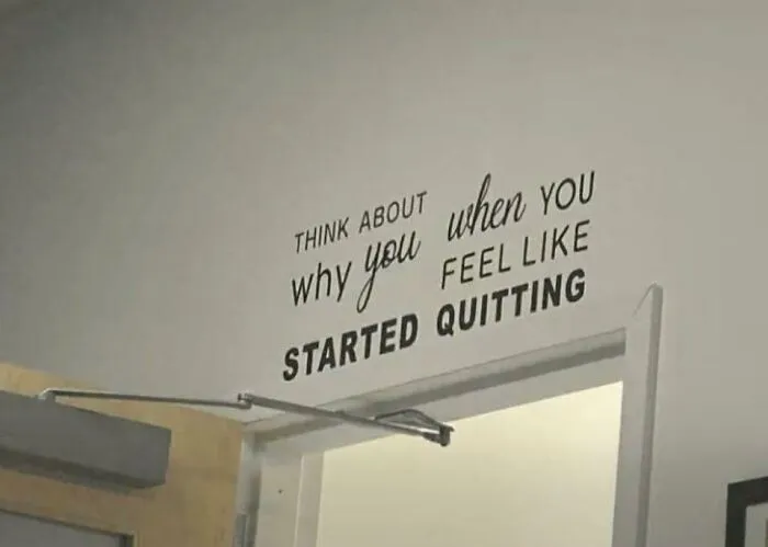 A wall decal with poorly formatted inspirational text above a doorway, featuring terribly designed signs.