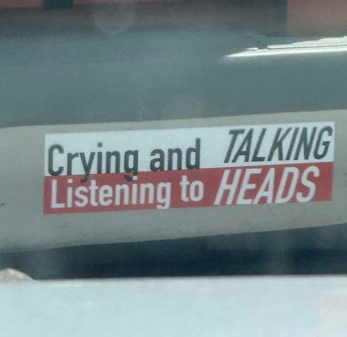 A car sticker reading Crying and TALKING Listening to HEADS, showing terribly designed signs.