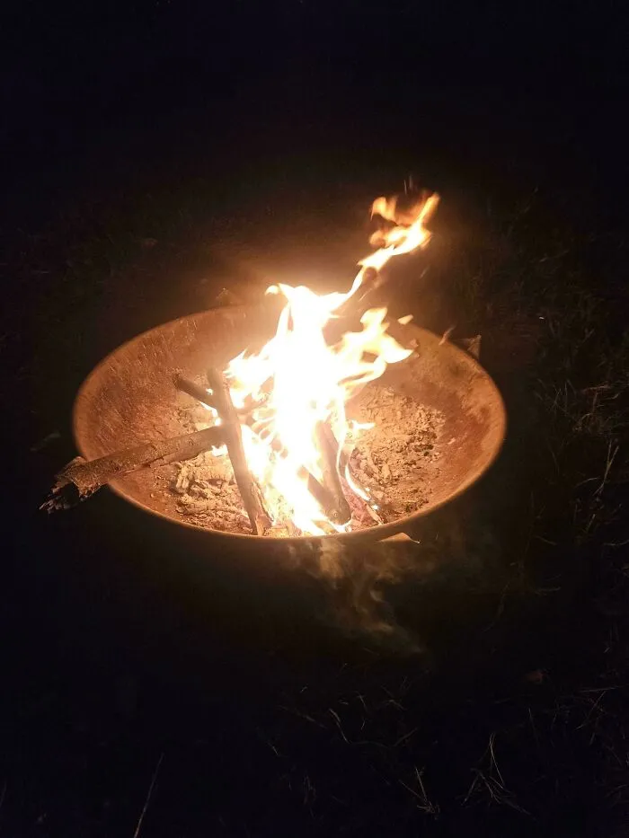 A glowing fire pit at night representing wholesome pics of dads setting up a campfire for family time