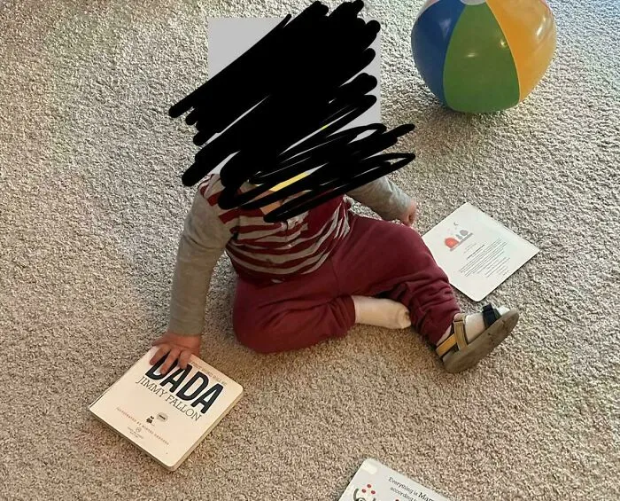 A young toddler sitting on the carpet playing with children books, capturing wholesome pics of dads.