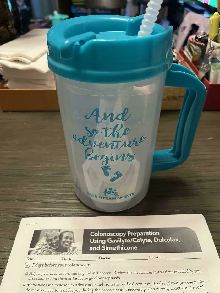 A hospital souvenir plastic mug on top of a colonoscopy preparation sheet, showcasing wholesome pics of dads.