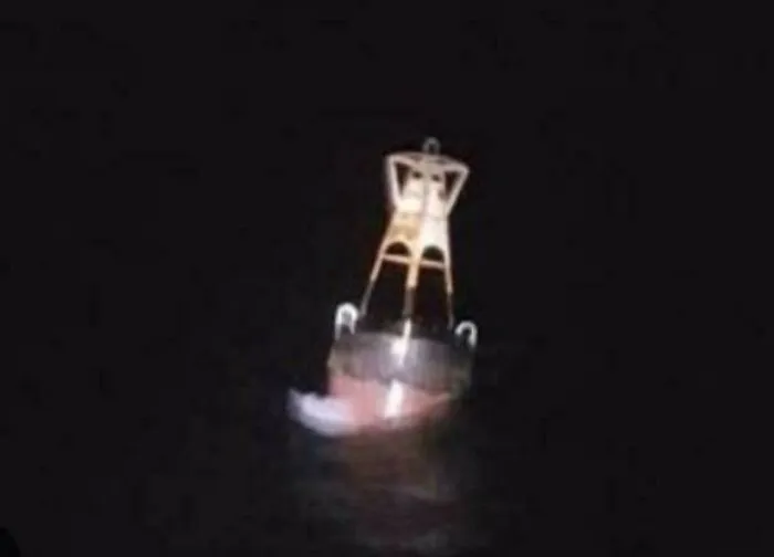 An eerie navigational buoy floating at night, representing unnerving submerged objects.