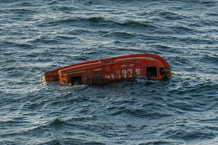Orange life raft floating capsized on the ocean surface, illustrating submechanophobia and fear of submerged objects