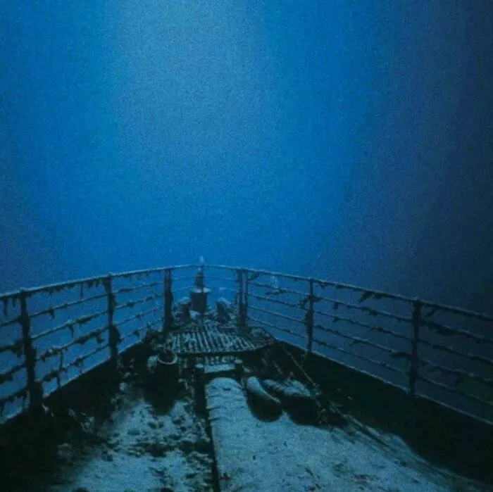 Bow of the sunken Titanic shipwreck resting in the dark ocean depths, showcasing unnerving submerged objects