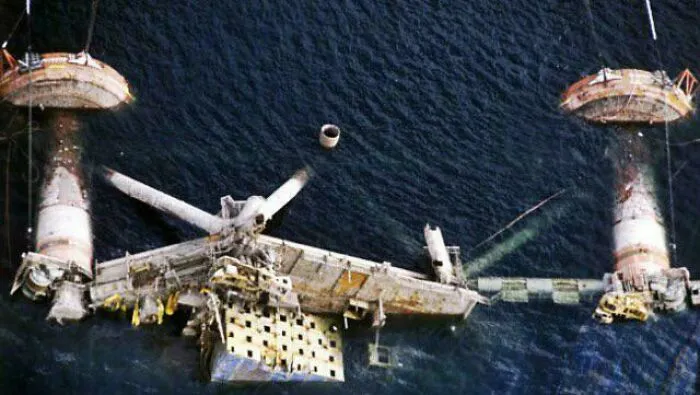 Aerial view of a massive partially submerged oil rig structure resting underwater.