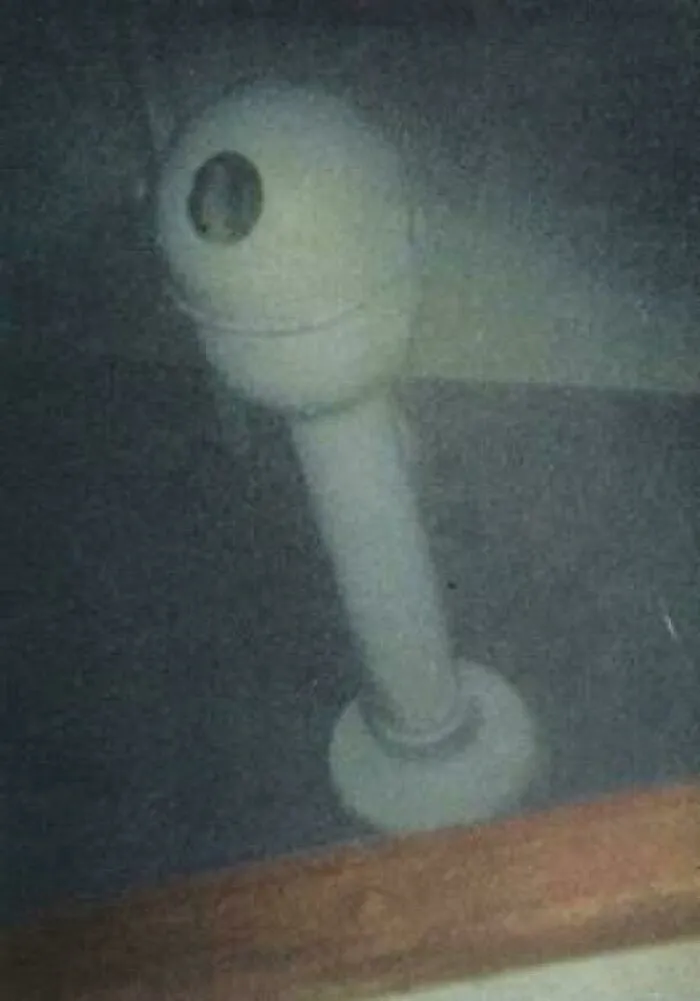 A hazy underwater view showing submerged objects like a pipe or periscope structure in dark murky water