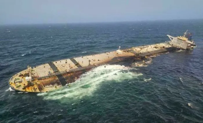A large cargo ship capsizing in open sea water, showing unnerving submerged objects.