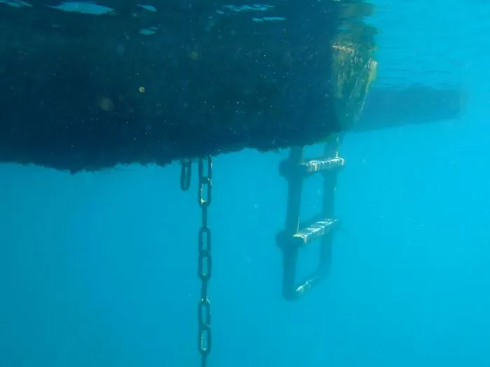 Underwater view showing submerged objects like a metal chain and ladder hanging below a boat.