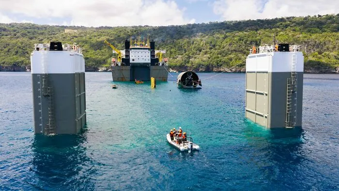 Large maritime floating dock with submerged objects resting in clear ocean water.