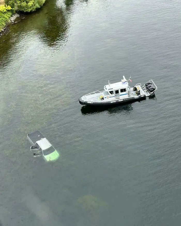 Police boat patrolling near submerged objects including a car visible under water
