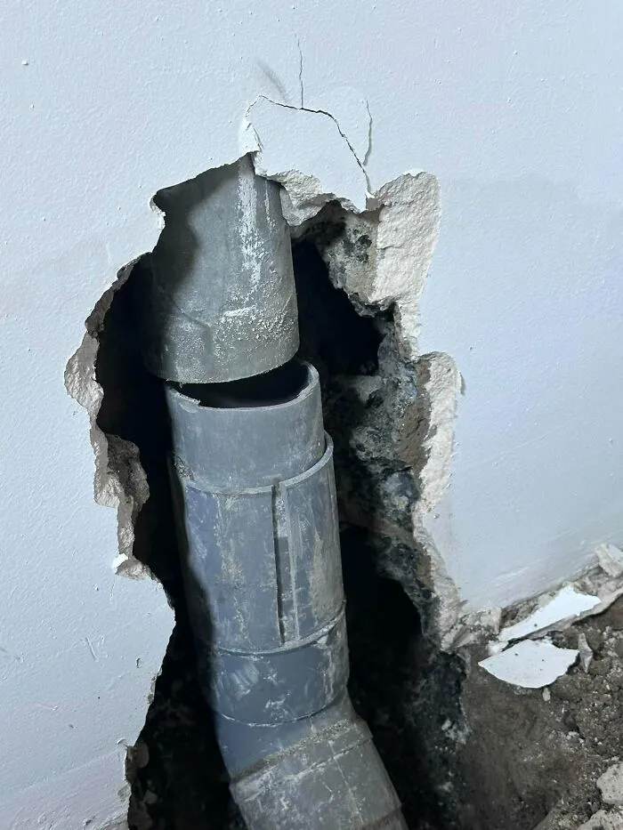Broken indoor wall showing disconnected plumbing, an example of construction fails.