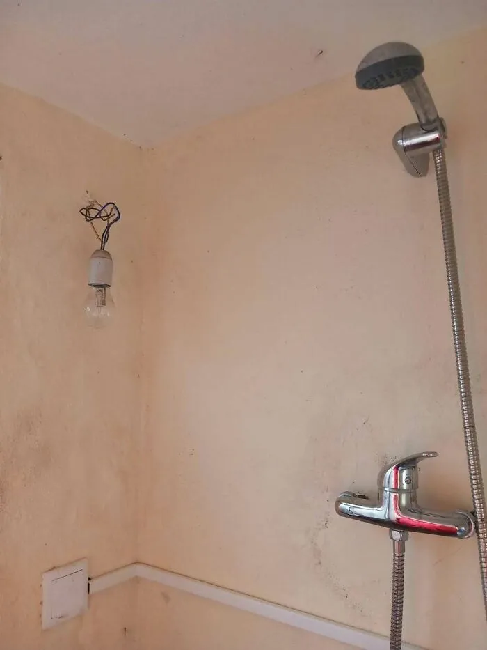 A lightbulb installed right next to a shower head showing major construction fails.