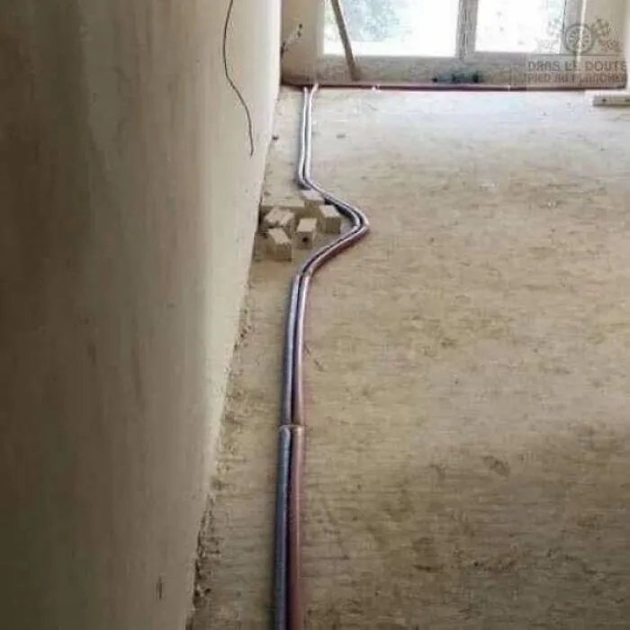 Pipes laid carelessly across a room floor as an example of construction fails.