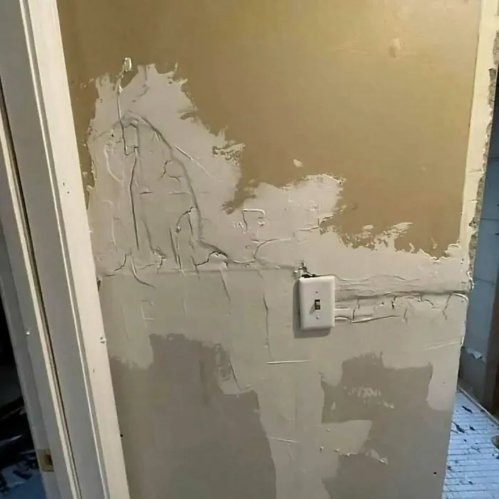 Badly plastered drywall around a light switch showing hilarious construction fails.