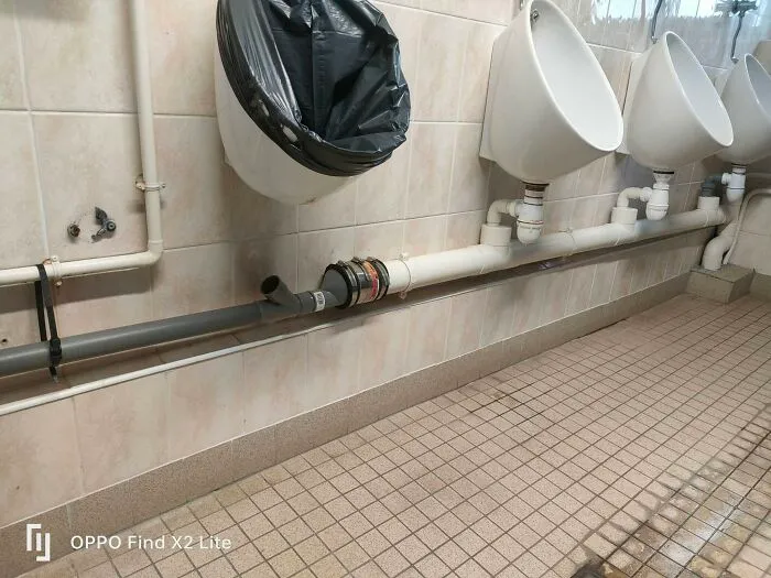 A trash bag lined urinal next to others, highlighting funny construction fails.