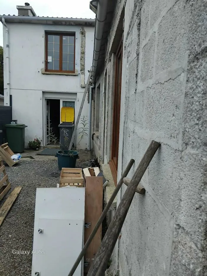 Messy outdoor alleyway near a building under renovation, showing a construction fail.