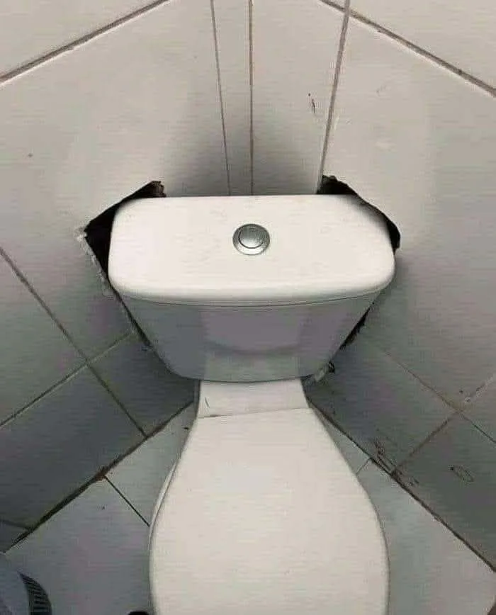 A toilet tank shoved into a rough cutout in the wall, an amusing construction fail.