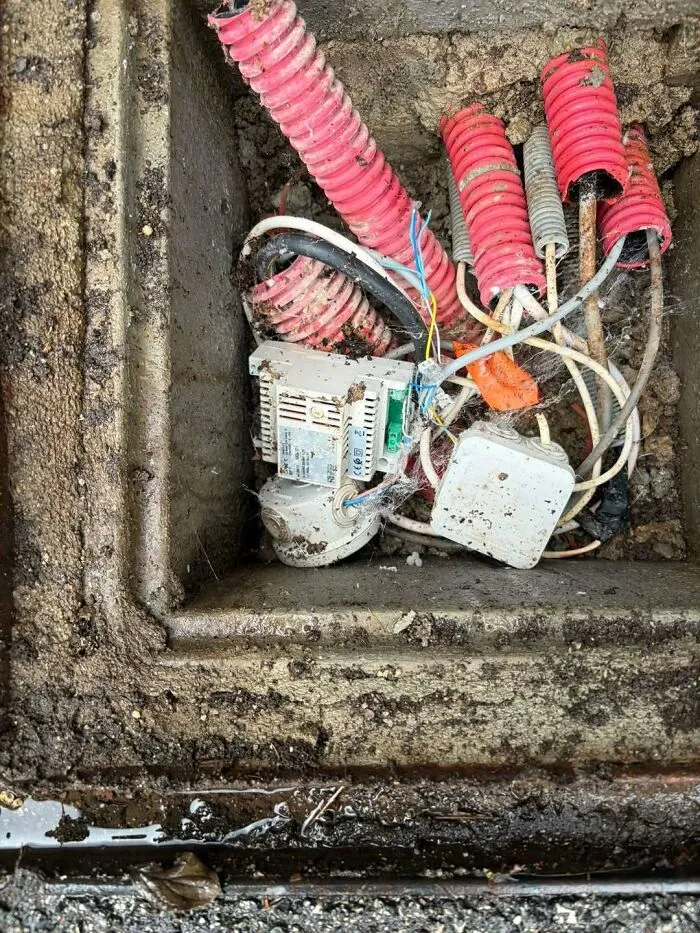 Tangled electrical wiring submerged in a dirty pit, a major construction fail.