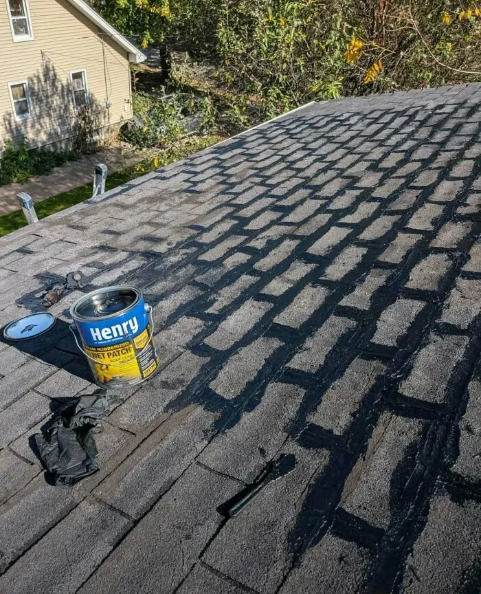 Roof shingles covered in sloppy black sealant as a construction fails example
