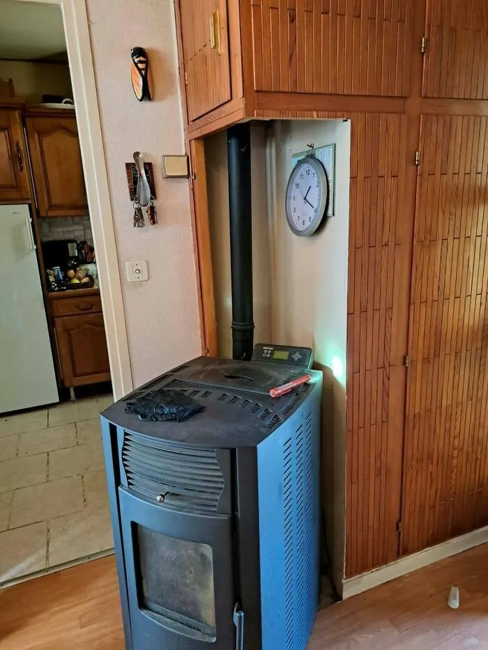 Pellet stove awkwardly installed into wooden cabinetry in a construction fails post